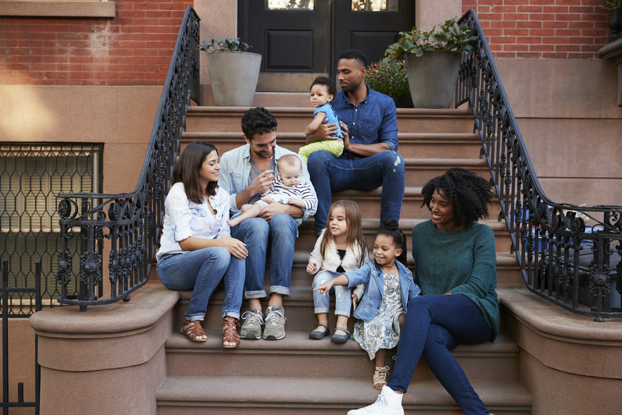 Two families with kids sitting on front stoops